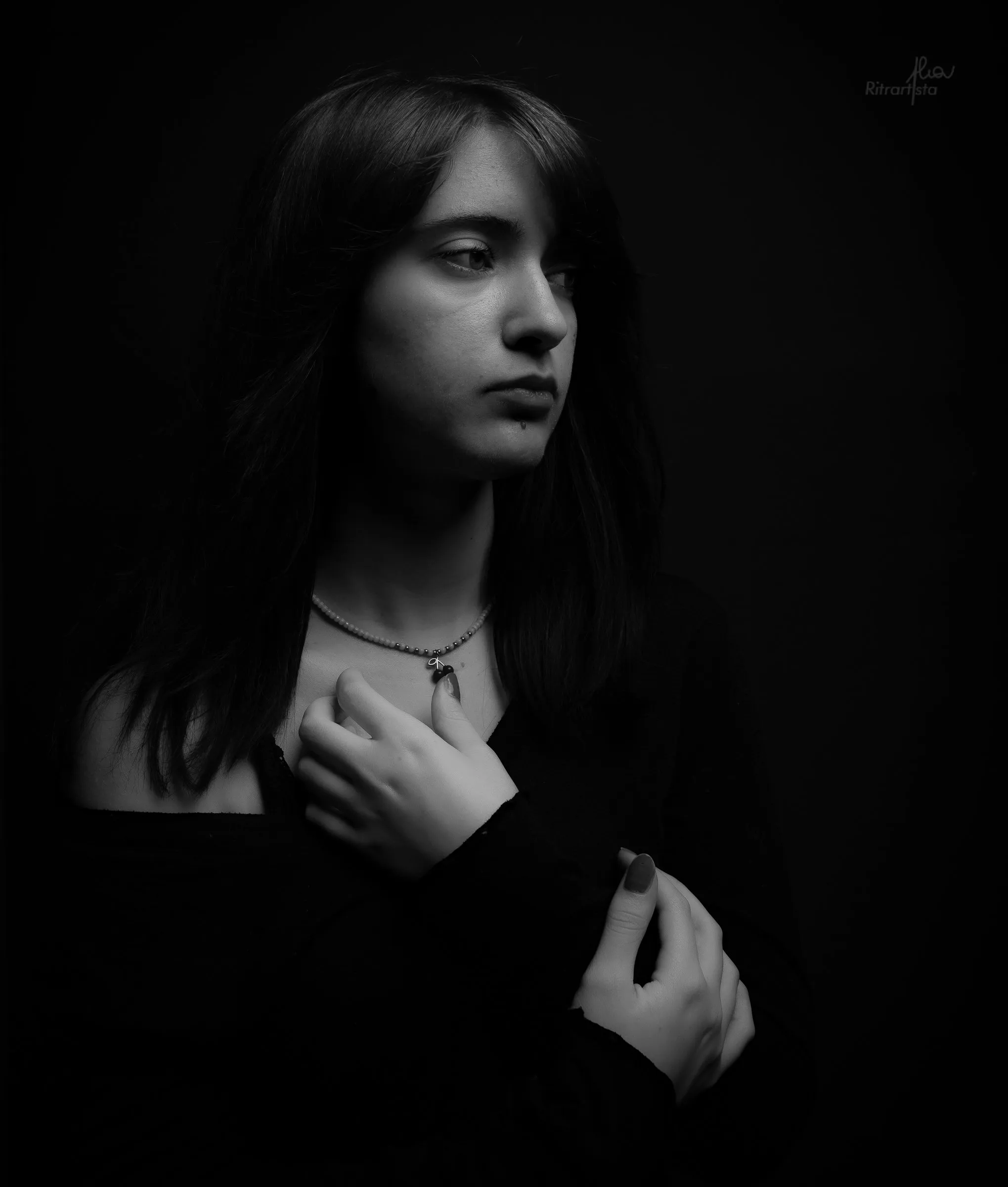 Ragazza in bianco e nero, luce laterale e mano sul petto