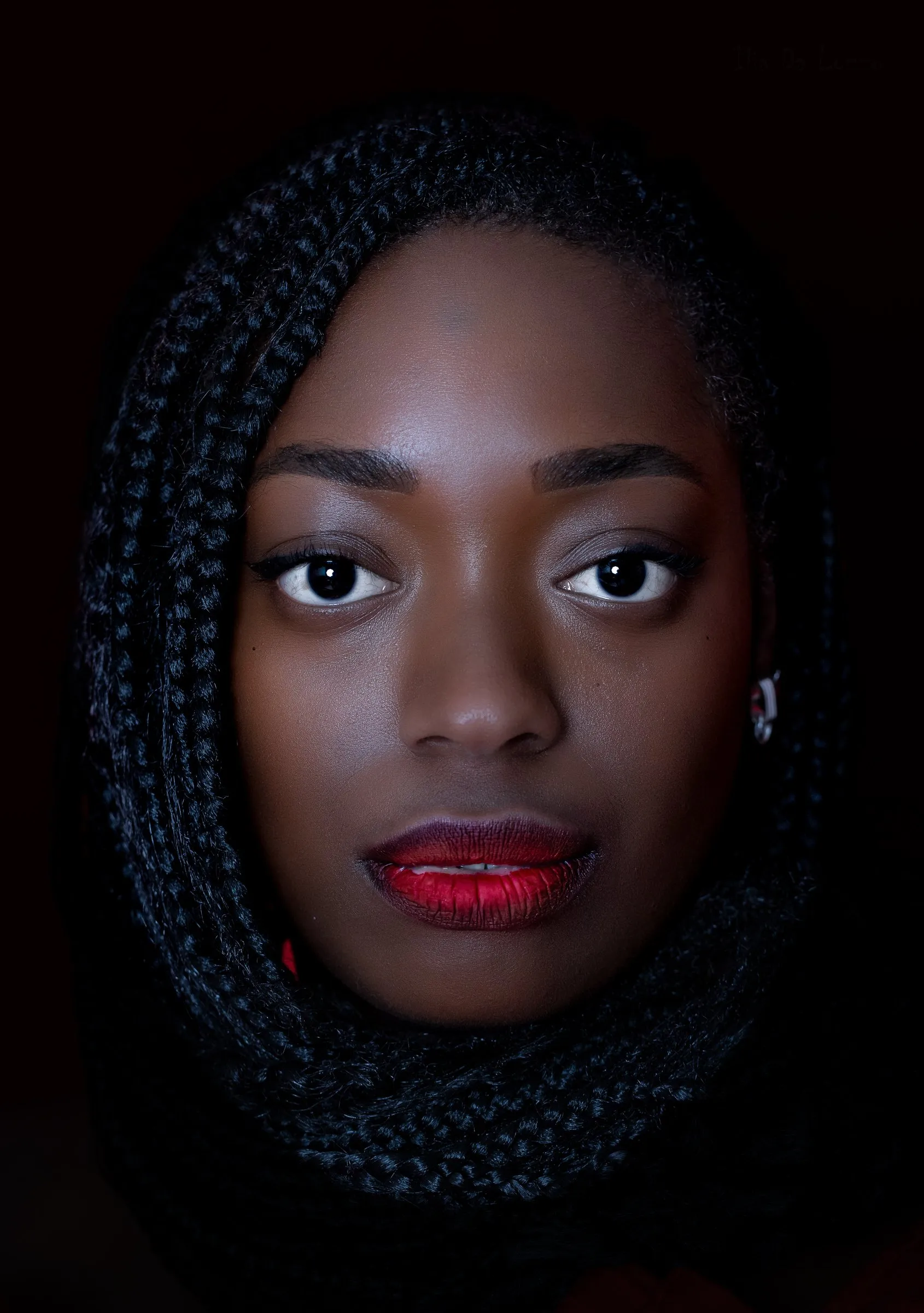 Donna con trecce raccolte nel foulard e labbra rosse, fondo scuro